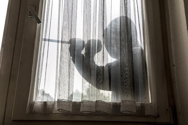 Ein Einbrecher macht sich an einem Fenster zu schaffen