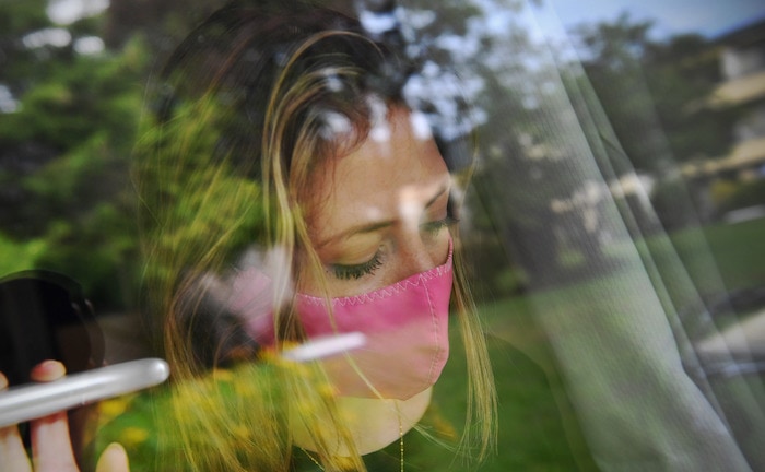 Frau steht mit Maske am Fenster