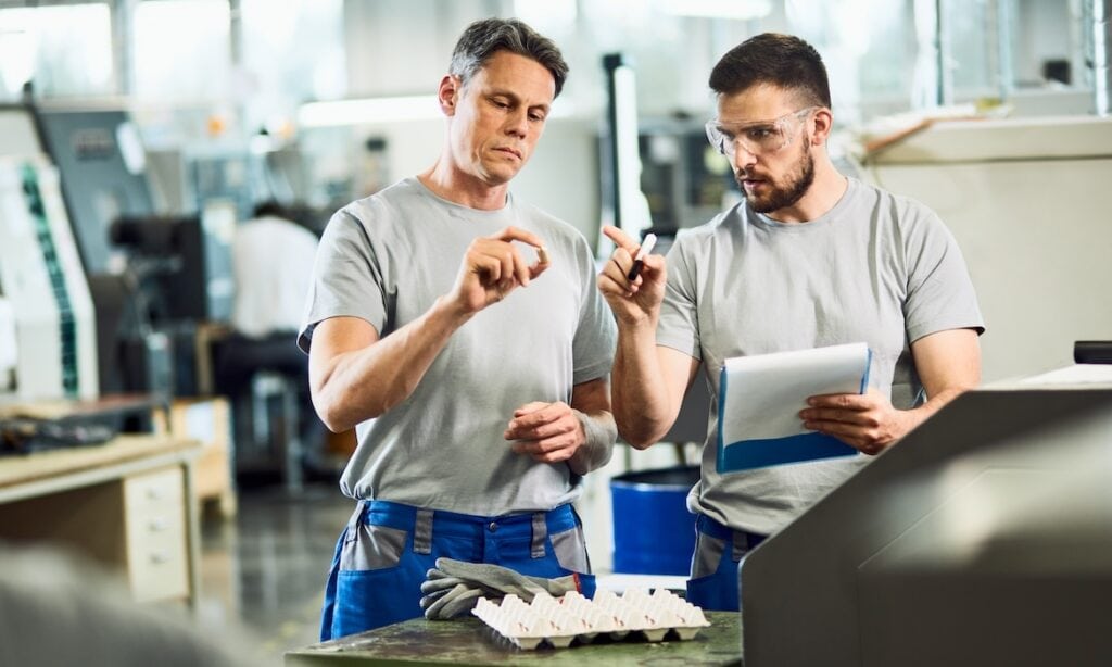 Zwei Männer arbeiten in einer Fabrik: Die DIN-Norm 77235 soll Versicherungsmakler dabei unterstützen, ihre Gewerbekunden besser zu beraten.