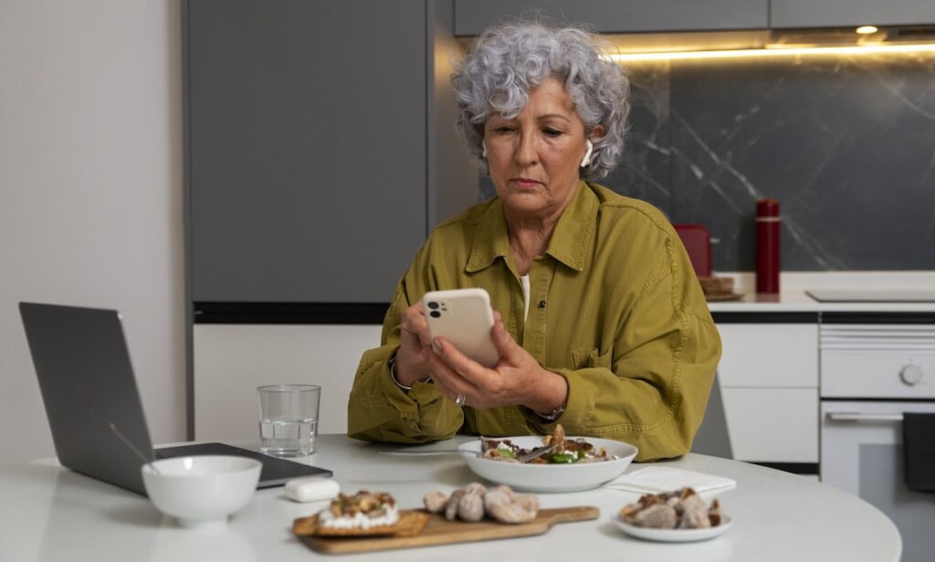 Rentner kontrolliert ihr Smartphone: Auch Rentner, die in Vollzeit gearbeitet haben, haben teils finanzielle Schwierigkeiten im Ruhestand.