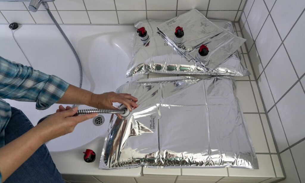 Ein Mann befüllt einen 10-Liter-Wasserbeutel mit Trinkwasser, um bei einem Blackout oder ähnliches gewappnet zu sein.