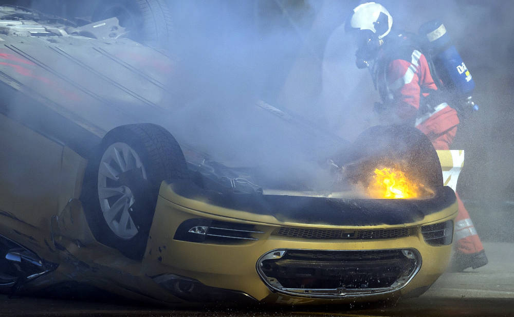 Auto bei Unfall in Brand, Feuerwehr löscht Fahrzeug, Gefahr durch Feuer, Verkehrsunfall, Rettungskräfte im Einsatz.