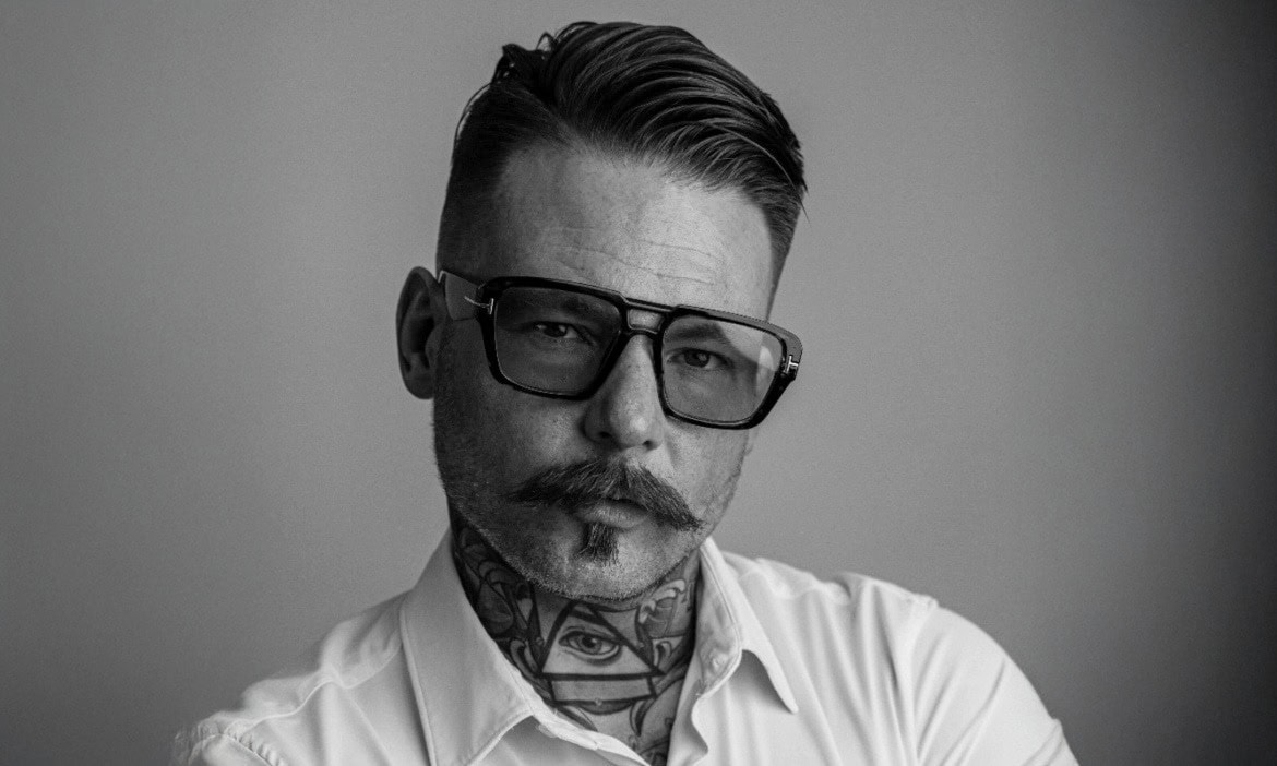 Edler Mann mit Brille und Tattoos, Schwarz-Weiß-Foto.