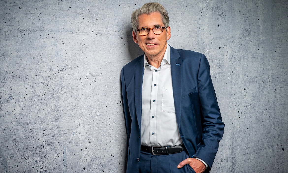 Mann in Anzug vor Betonwand, professionell und kompetent.