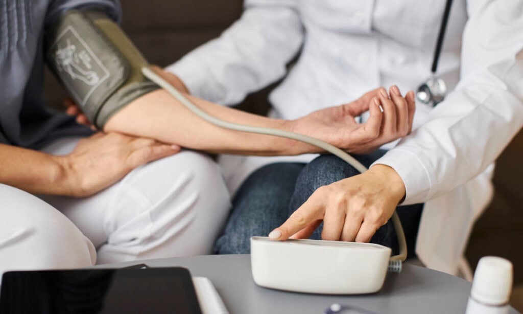 Arzt misst Blutdruck bei Patient im Sprechzimmer.