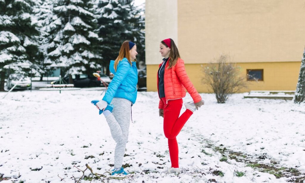 Zwei Frauen im Winterkleidung sprechen sich auf verschneitem Gelände ab.