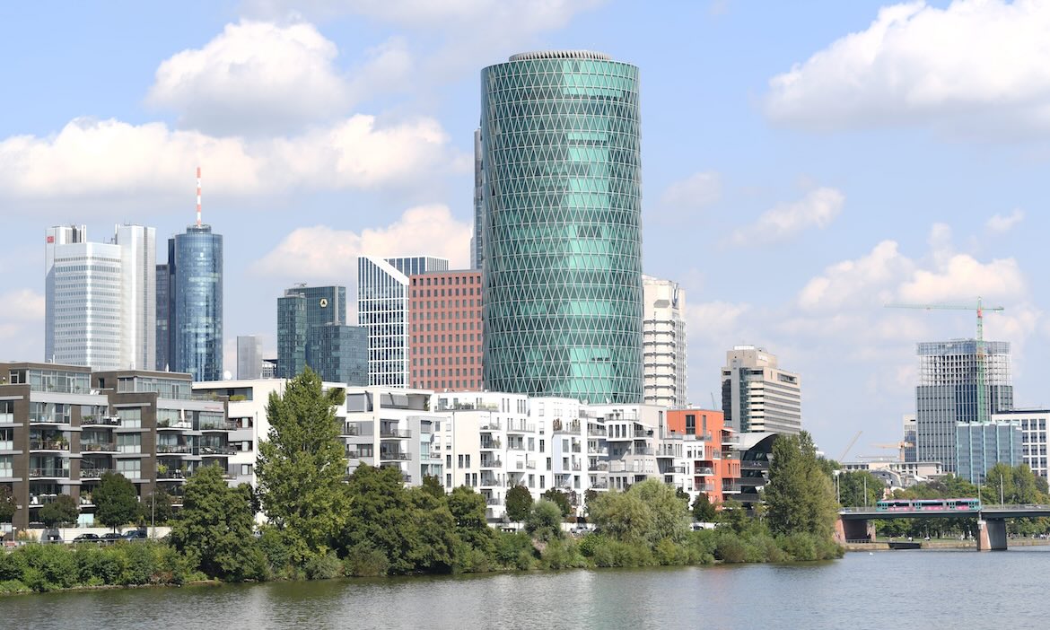Moderne Frankfurter Skyline mit Hochhäusern und Fluss im Vordergrund.