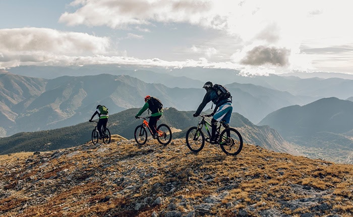 Abenteuerliche Mountainbiker auf einer Bergkuppe mit Blick auf die Alpen. Perfekt für Outdoor- und S.