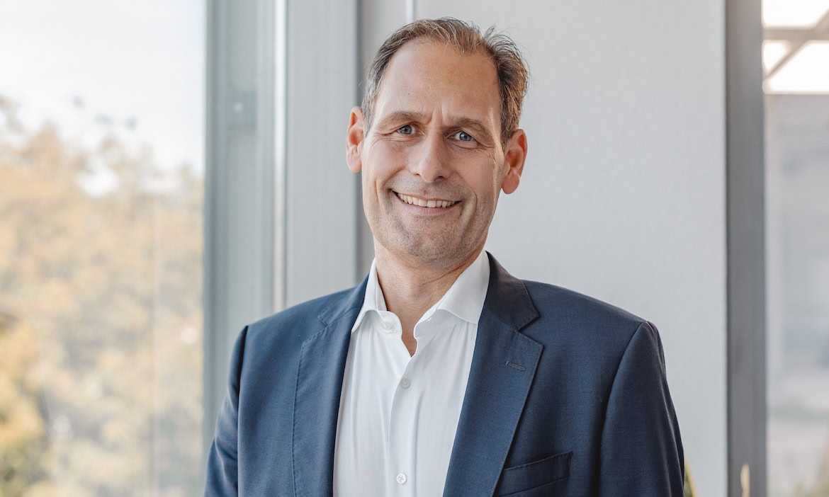 Erfolgreicher Finanzberater in Business-Umgebung, smiling, professionell gekleidet.