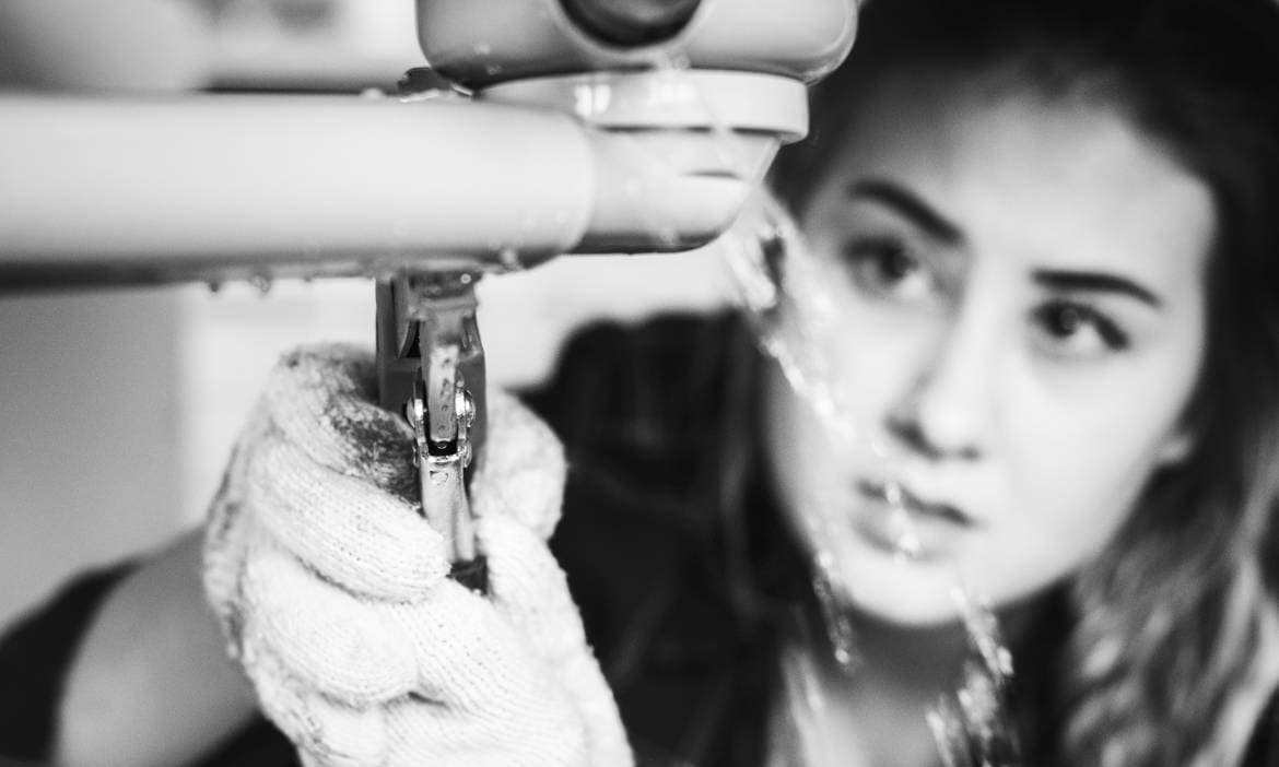 Frau repariert Wasserleitung, Wasserschaden, Handwerk, Hausreparatur.