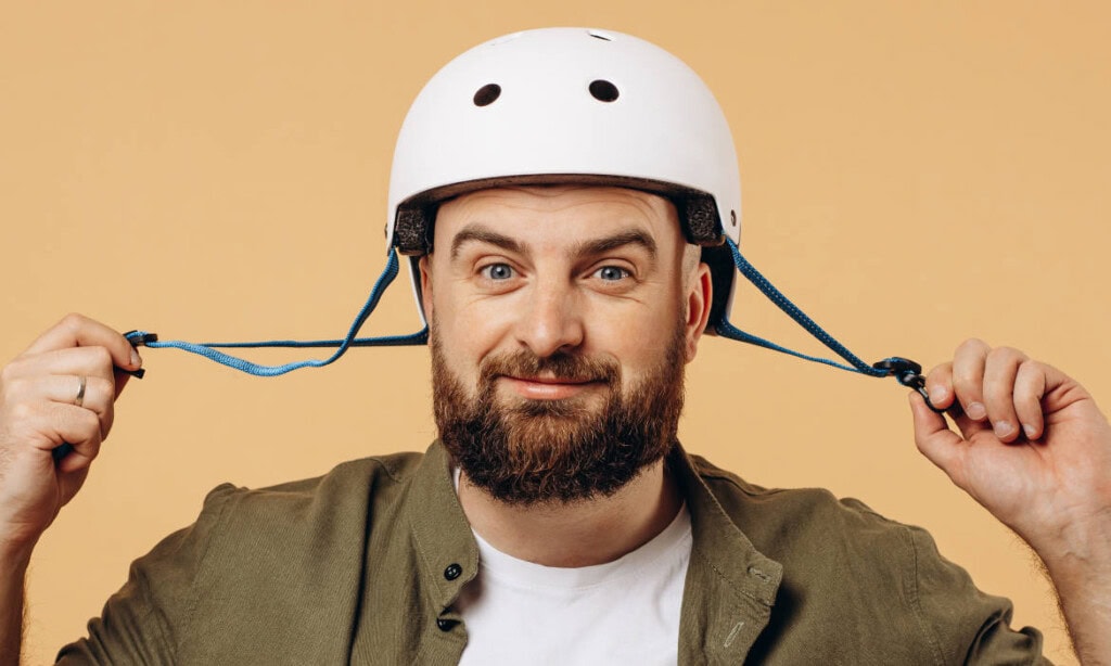 Mann mit Helm, symbolisiert Sicherheit bei Geldanlagen, lächelt freundlich.