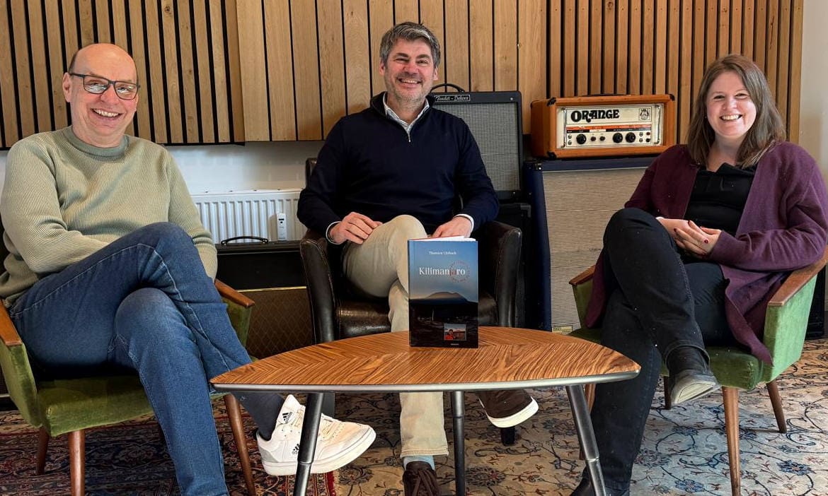 Drei Personen im Gespräch bei Podcast-Aufnahme im Studio.