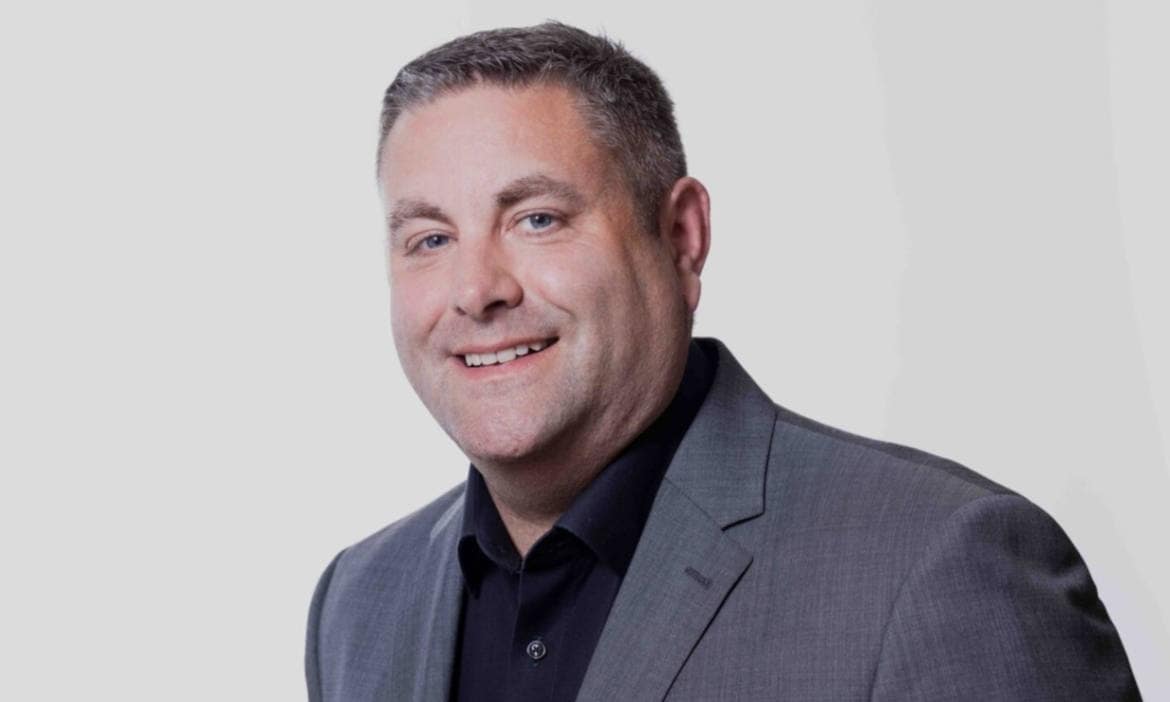 Mann in Anzug erklärt Hausratversicherung und Neuwert bei Schadensfällen.