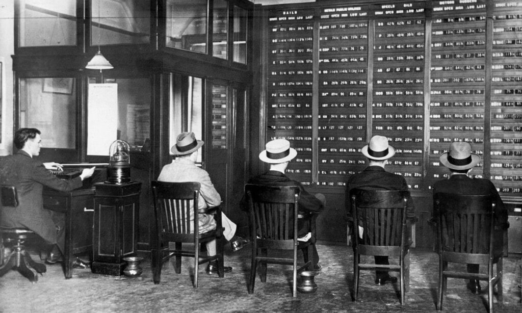Frauen warten in einer historischen Bankfiliale auf Aktienberatung.