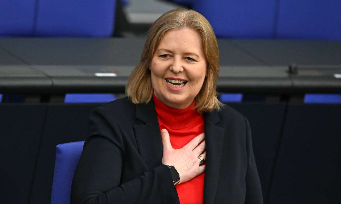 Frau lächelt, während sie auf eine Rentenerhöhung zum 1. Juli 2026 hinweist.