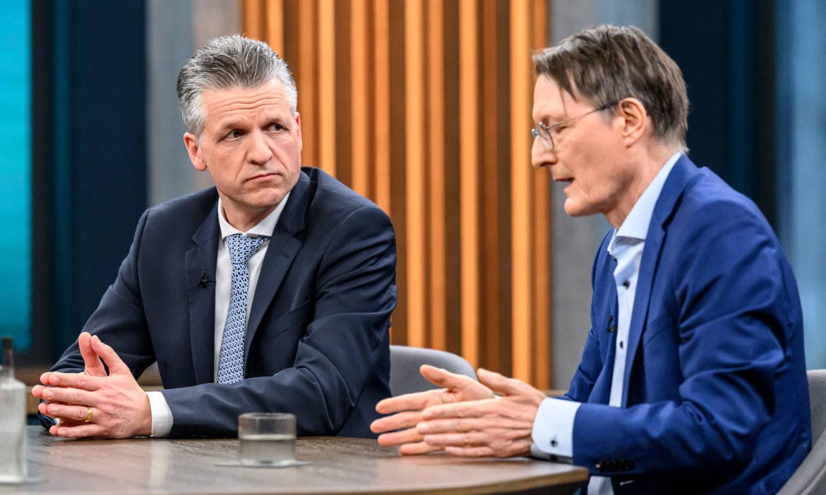 Zwei Männer im Gespräch, einer erklärt etwas, im Hintergrund ein moderner Raum.