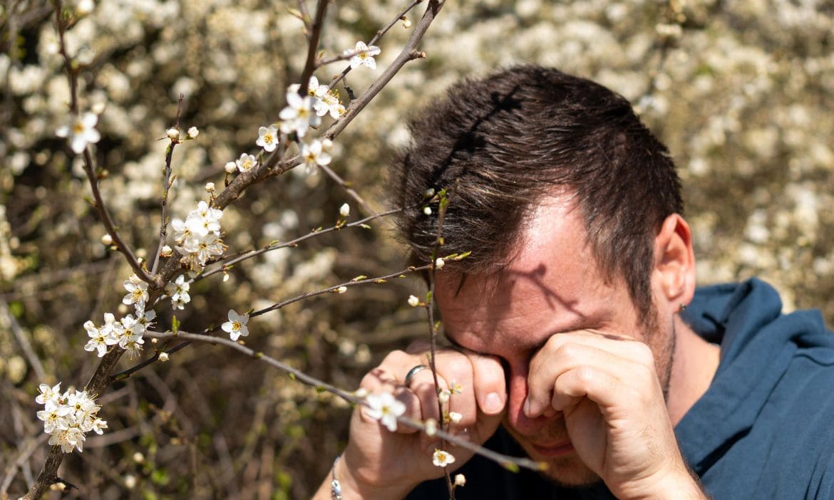 Allergiker leidet an Heuschnupfen, niest und reibt die Augen im Frühling.