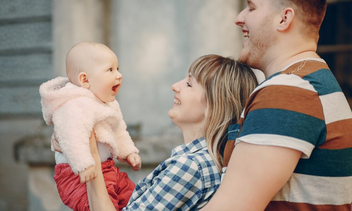 Lächelnde Familie mit Baby, die gemeinsam Freude und Liebe teilen.