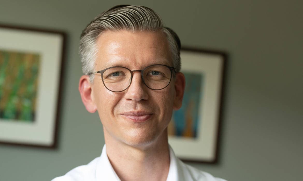 Expertenbild eines Mannes mit Brille, professionell und vertrauenswürdig, im Büro.