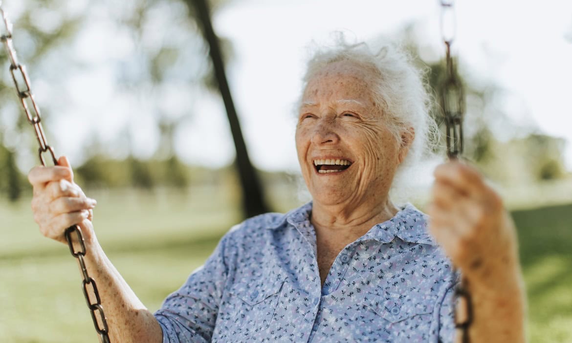 Glückliche ältere Frau schwingt auf einer Schaukel im Park.