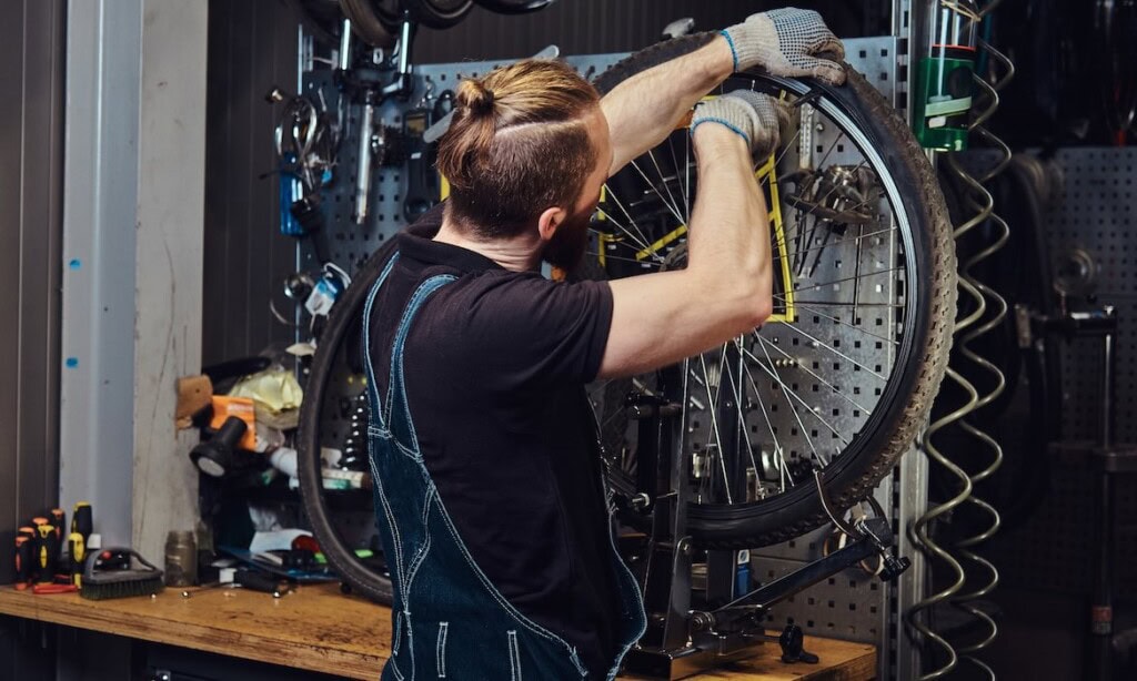 Fahrrad wird in Werkstatt repariert, Werkstatt mit Werkzeugen im Hintergrund.