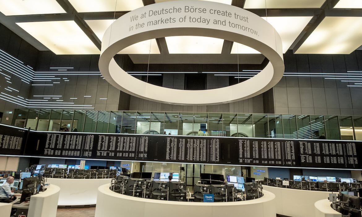 Blick auf den Handelsraum an der Deutschen Börse mit Anzeigetafeln und moderner Architektur.