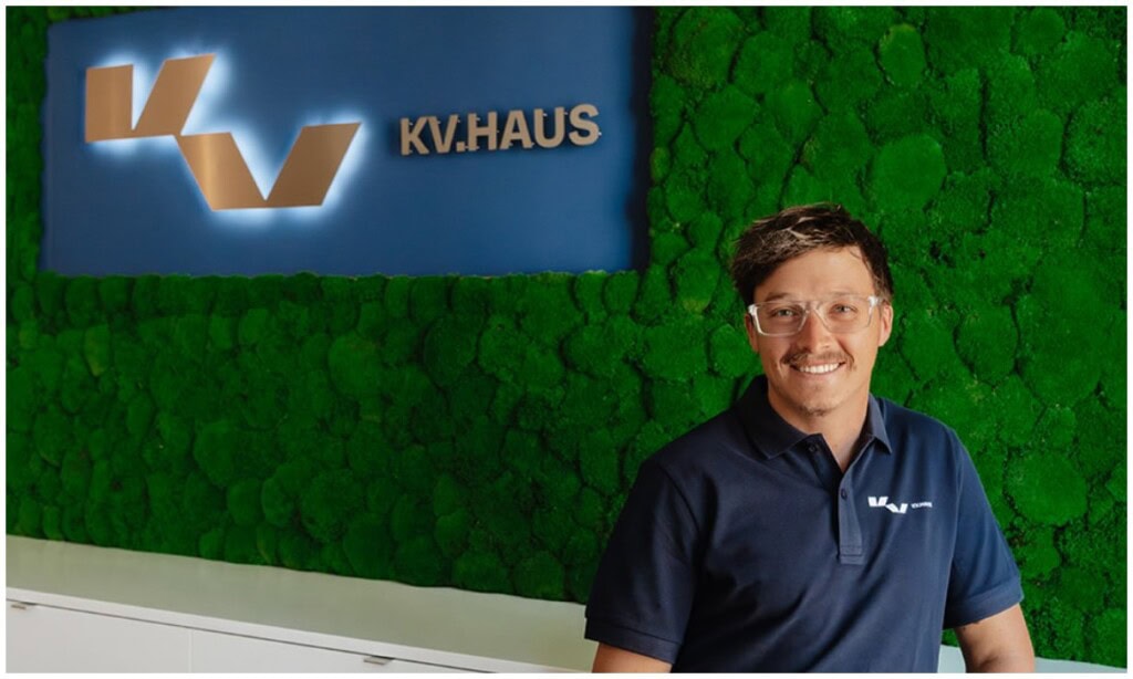 KV Haus Mitarbeiter vor grünem Wand mit Logo, passend zum Podcast-Thema ETF-Boom und digitaler Makle.