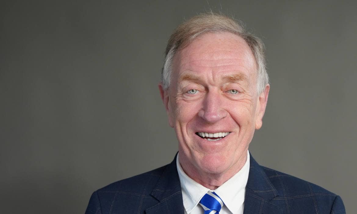 Älterer Mann in Anzug lächelt freundlich, professionell.