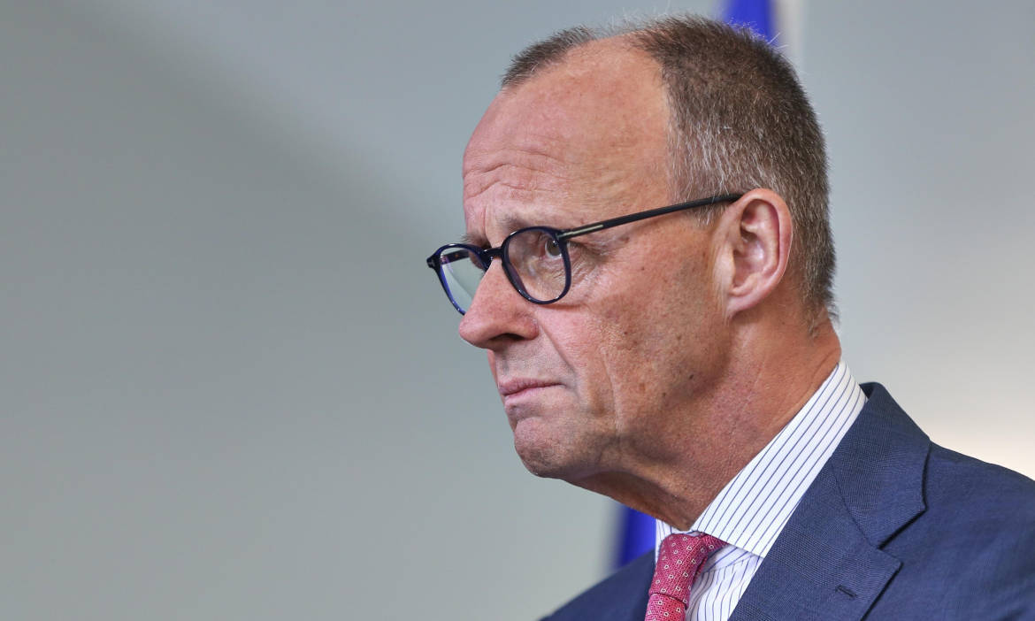 Friedrich Merz in Anzug und Brille bei einer Pressekonferenz.