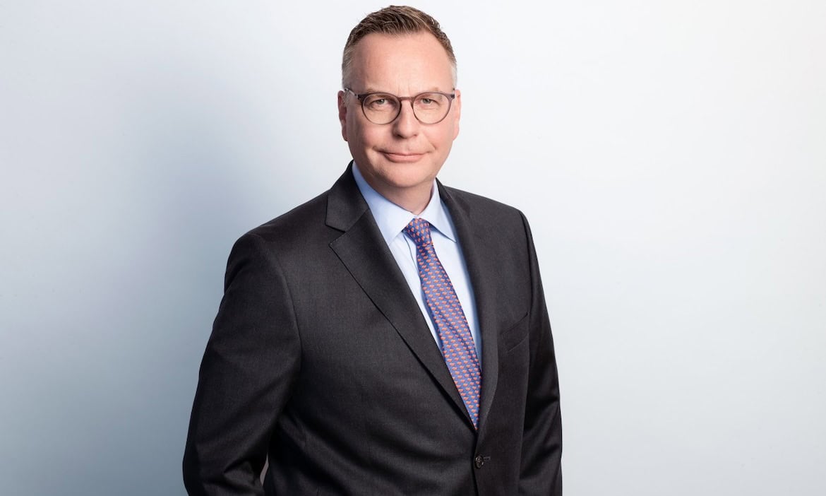 Geschäftsmann in Anzug vor hellem Hintergrund, symbolisiert Chancen im Maklermarkt.