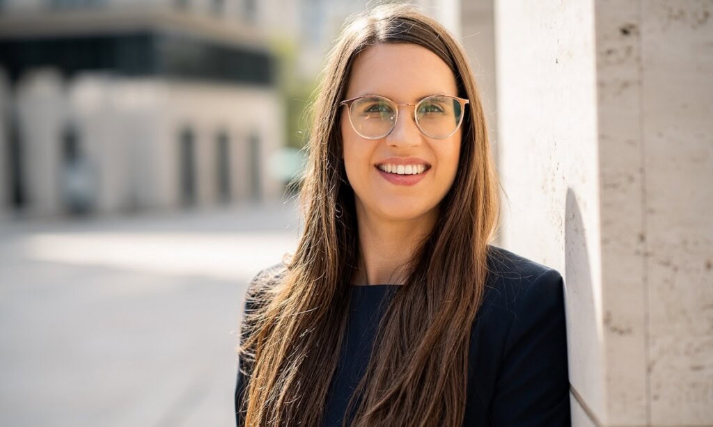 Frau mit Brille und dunklem Blazer vor urbaner Kulisse, professionelle Cyber-Expertin Rittger.