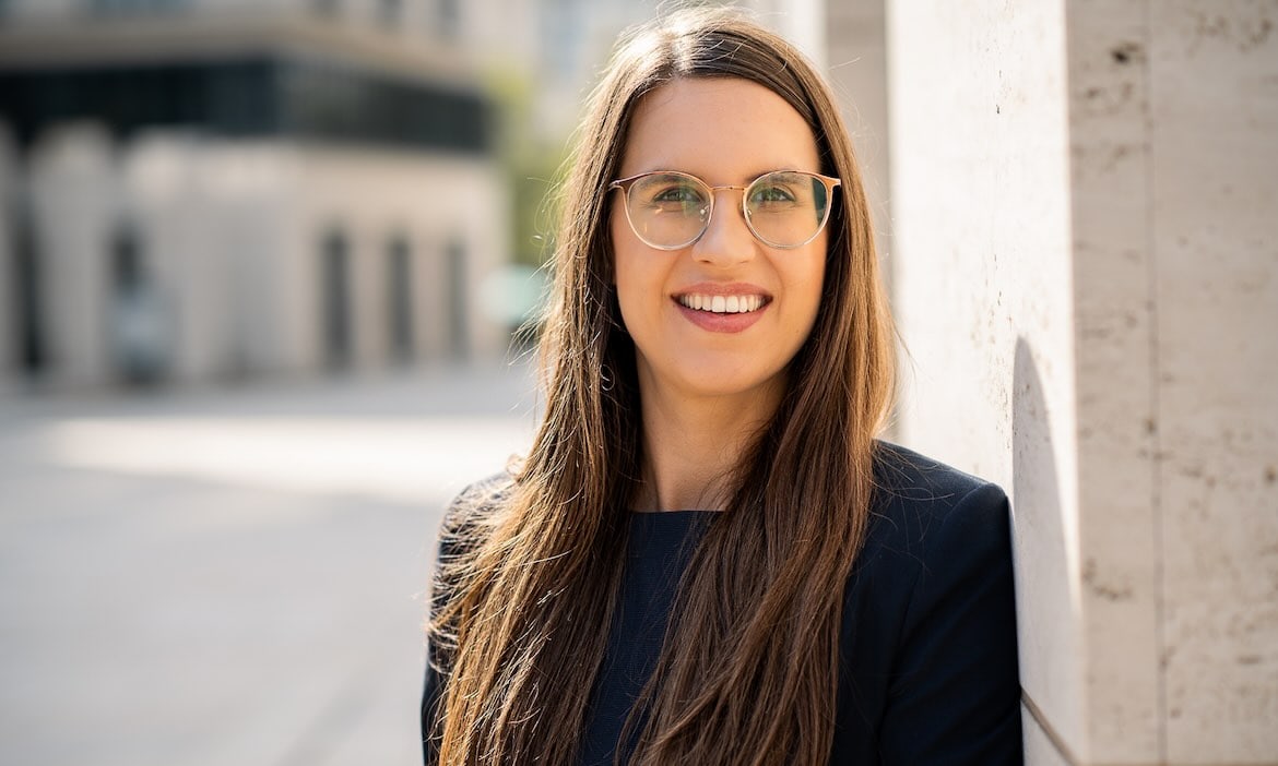 Frau mit Brille und dunklem Blazer vor urbaner Kulisse, professionelle Cyber-Expertin Rittger.