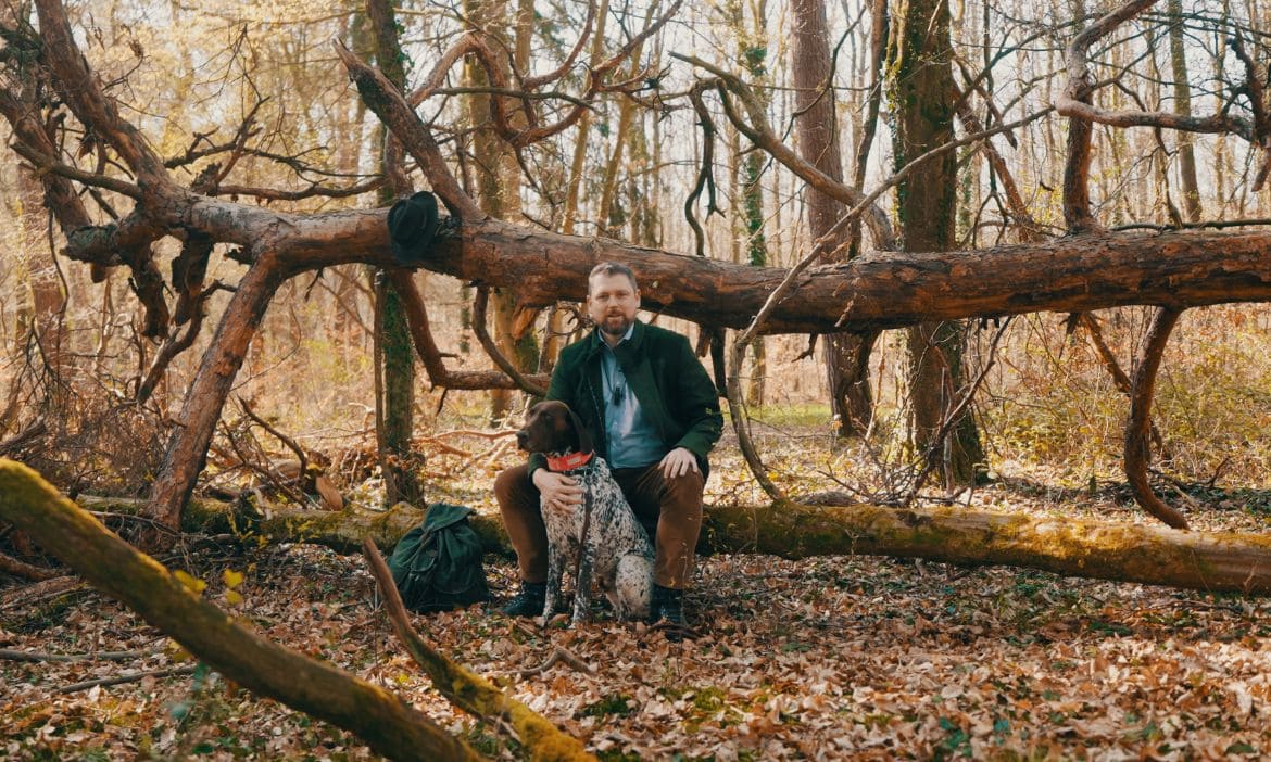Abenteuer im Wald mit Hund, Mann sitzt auf Baumstamm, Natur, Herbst, Outdoor.