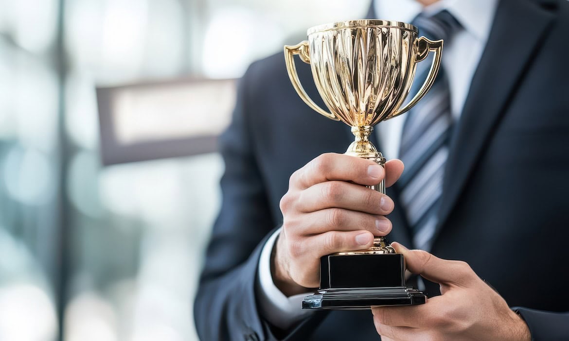 Mann hält Pokal, Symbol für ausgezeichneten Kundenservice und Versicherungsqualität.