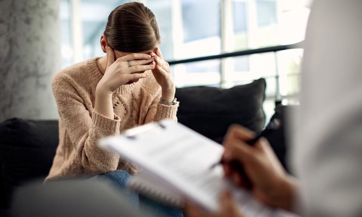Frau leidet unter psychischer Belastung, sucht Unterstützung bei Versicherung.