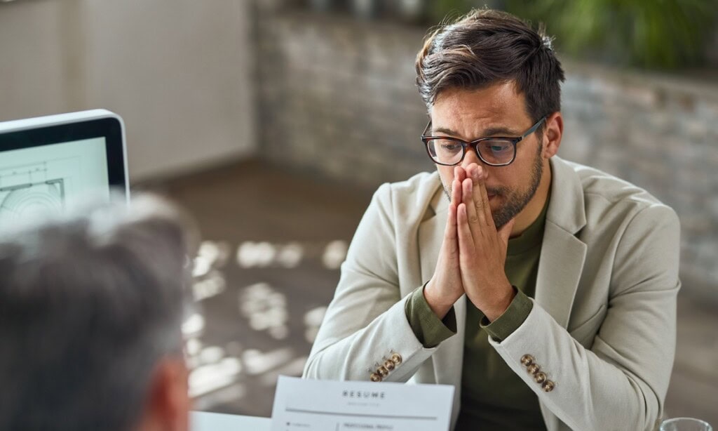 Mann mit besorgtem Gesicht hält Hände vor Mund, symbolisiert Stress bei Konflikten.