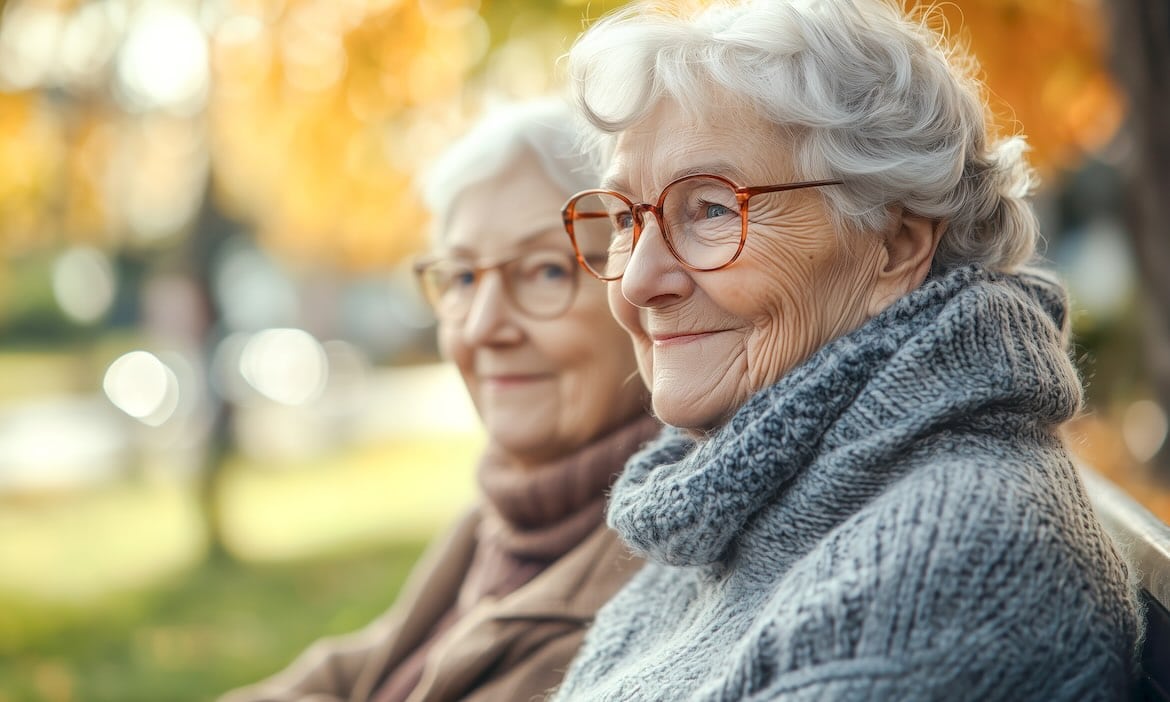 Zwei ältere Frauen im Park, die sich auf ihre Altersvorsorge freuen.
