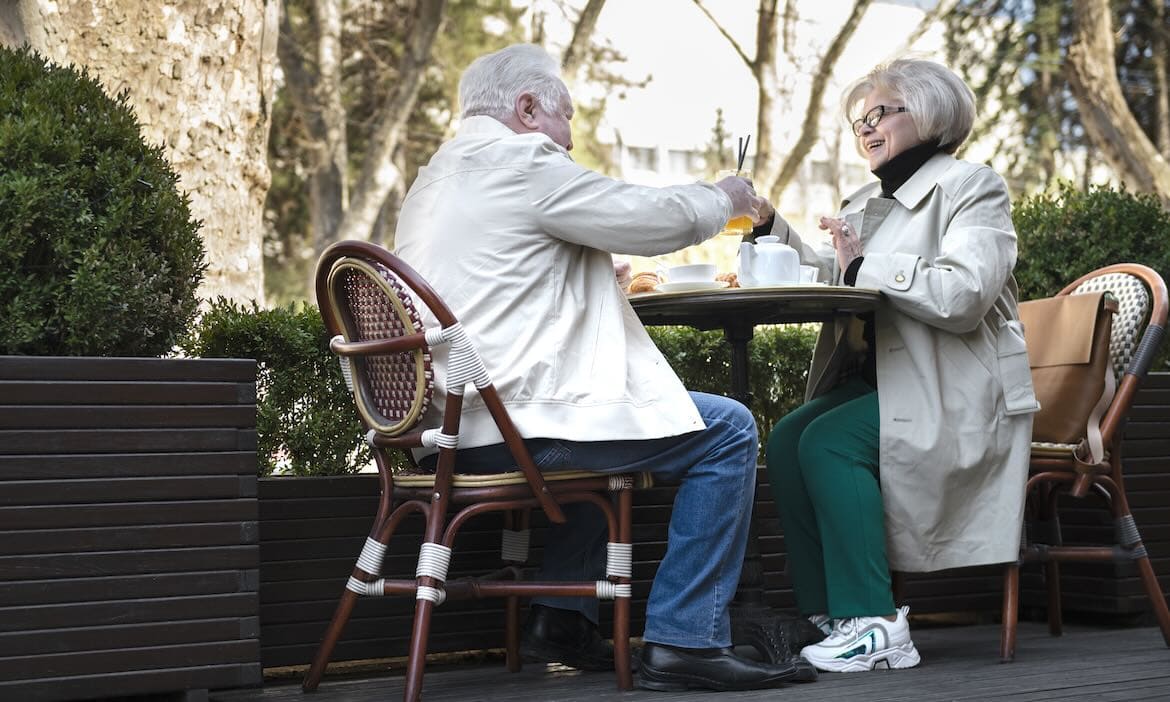 Älteres Paar beim Kaffee im Garten, Thema Altersvorsorge und finanzielle Sicherheit im Alter.