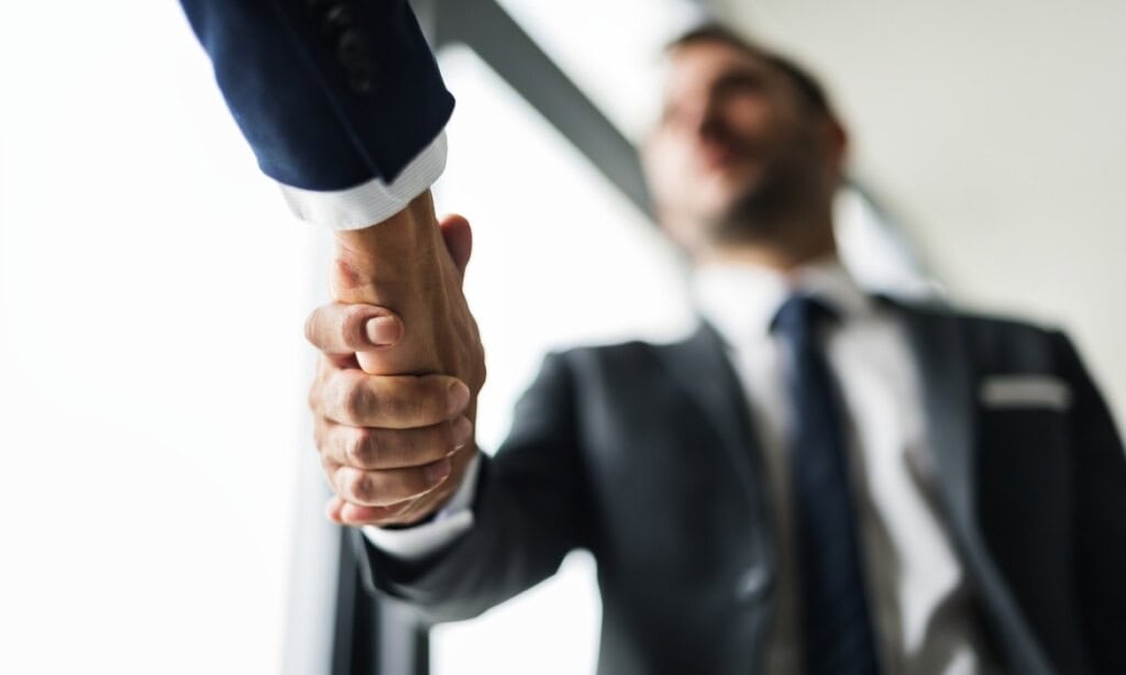 Geschäftsmann schüttelt die Hand eines Partners bei BCA, symbolisiert Zusammenarbeit.