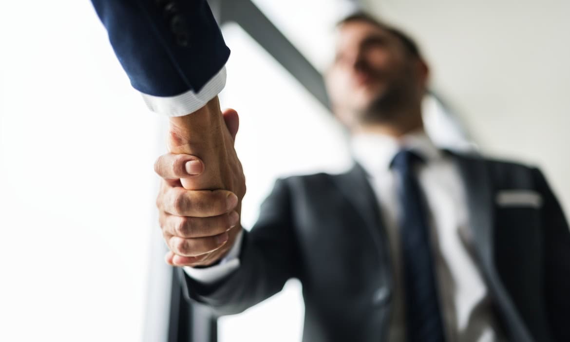 Geschäftsmann schüttelt die Hand eines Partners bei BCA, symbolisiert Zusammenarbeit.