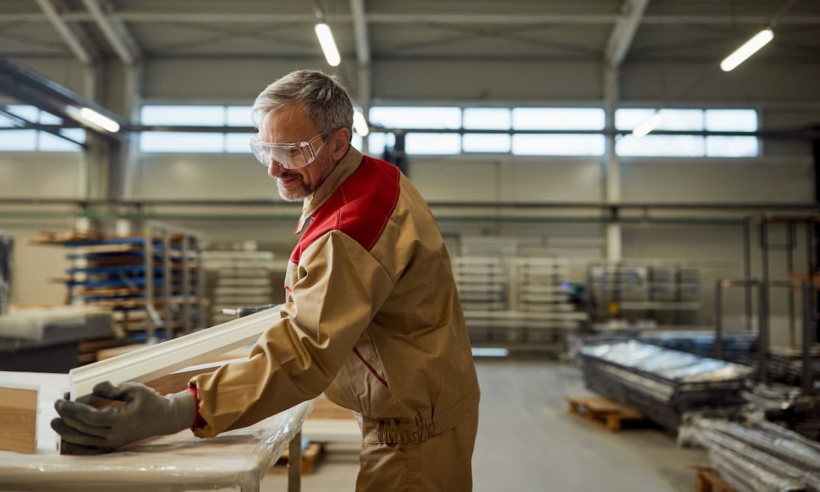 Handwerker prüft Holz im Produktionsraum für bessere bAV- und bKV-Lösungen.
