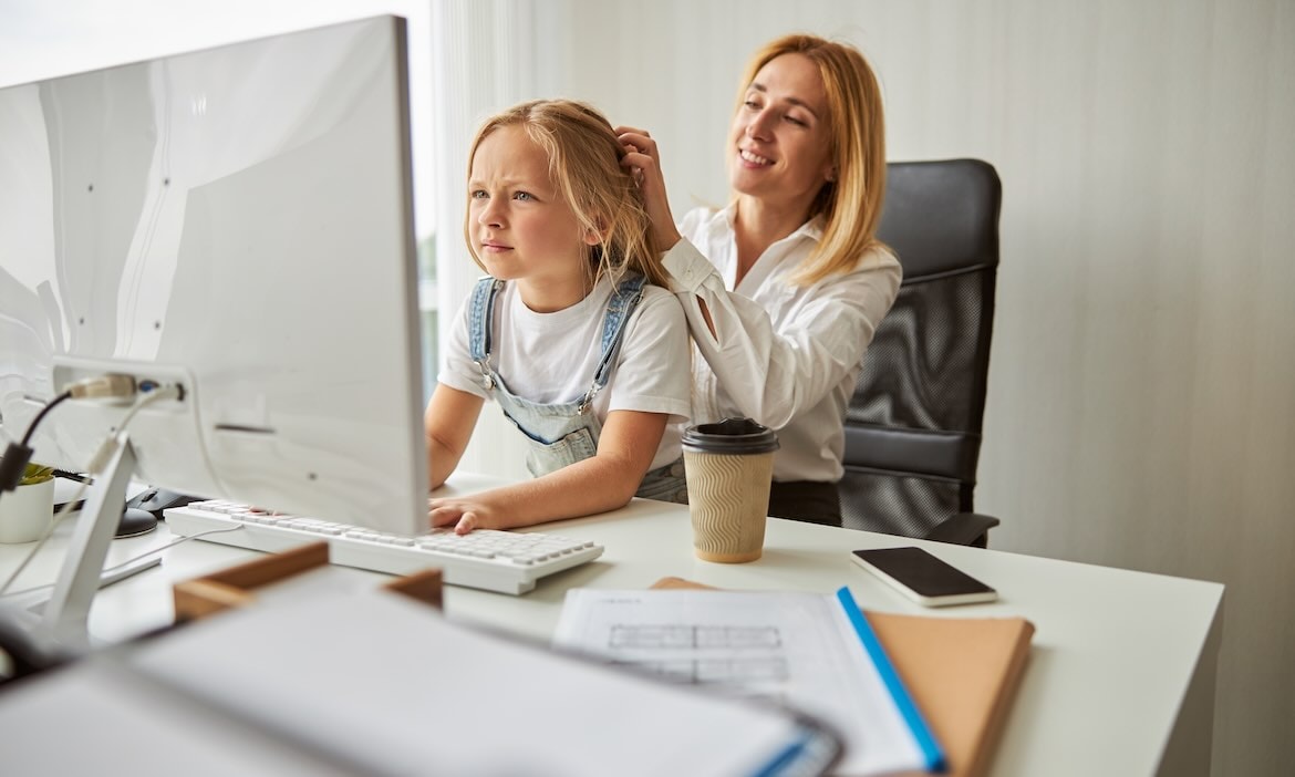 Frau hilft Kind am Computer bei der Arbeit, symbolisiert die Auswirkungen einer Teilzeitkarrierepaus.