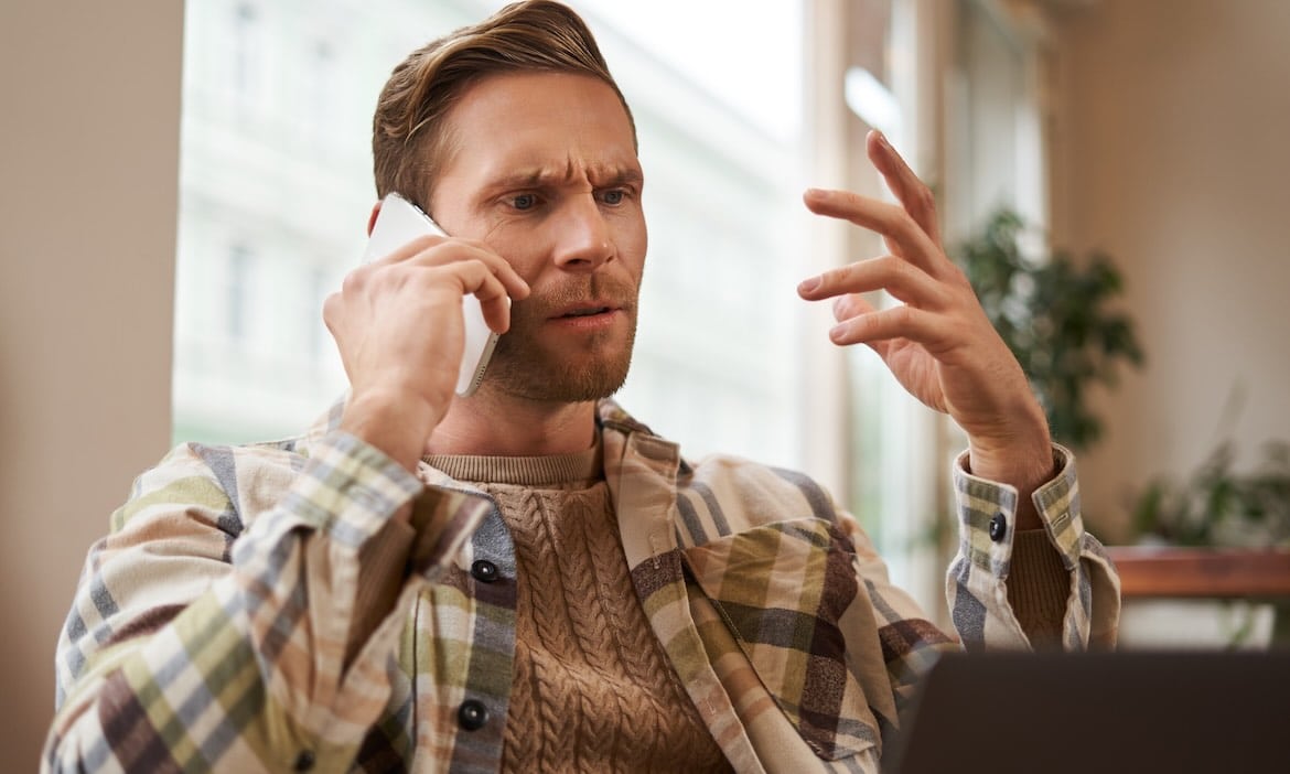 Nachdenklicher Mann spricht am Telefon über Versicherungsprobleme.