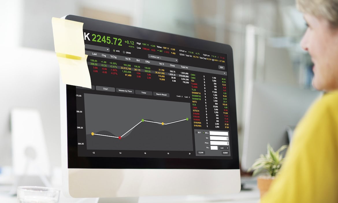 Frau analysiert Börsendaten auf einem Computerbildschirm.