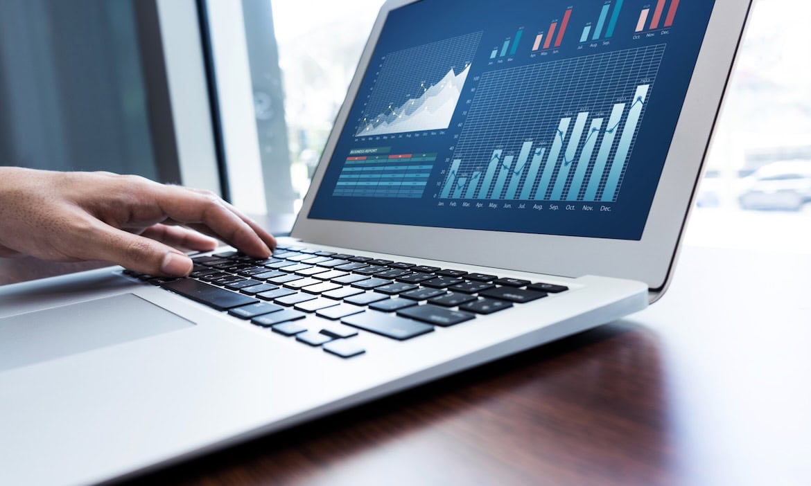 Person analysiert Finanzcharts auf Laptop für unterschiedliche Anlageentscheidungen.