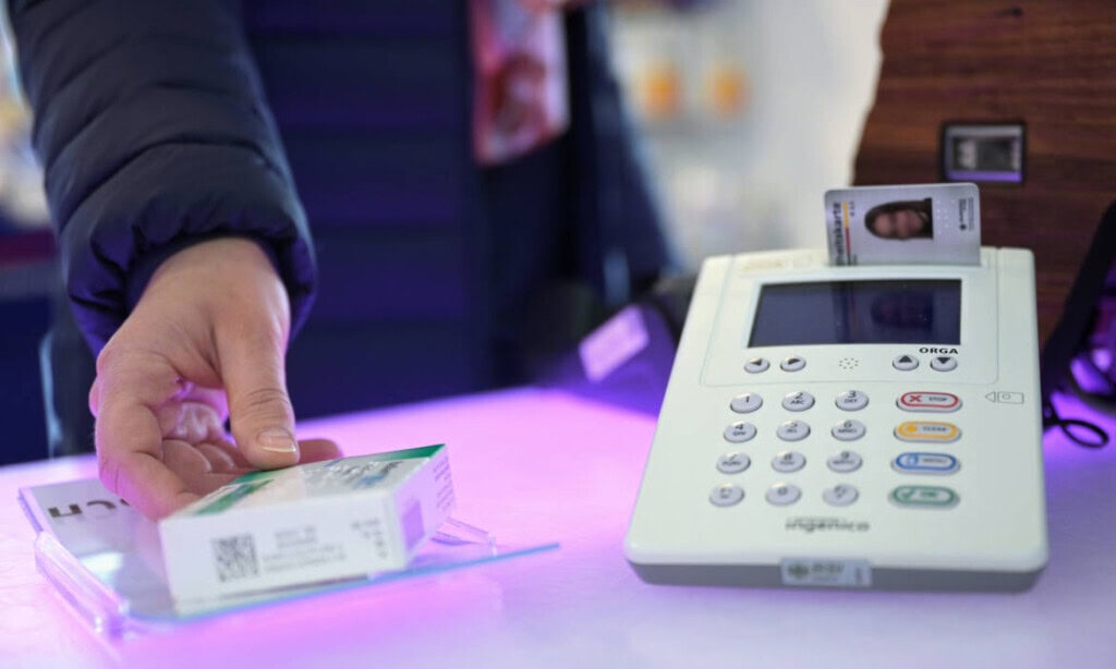 Person bezahlt an der Kasse mit Kreditkarte, Kassenterminal im Hintergrund.