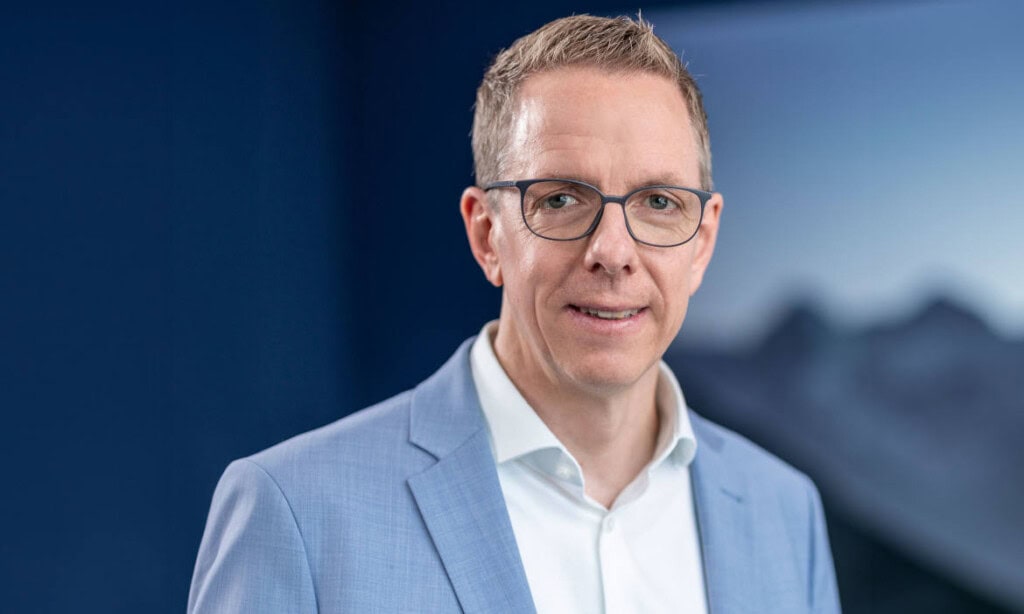 Innovativer Geschäftsmann in Business-Anzug vor modernem Hintergrund.