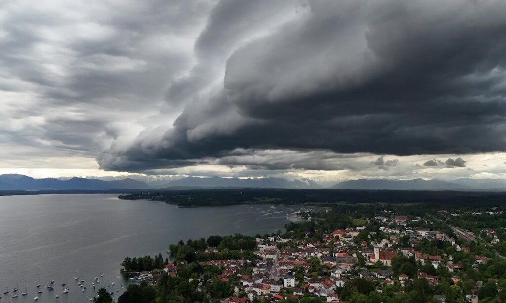 Dunkle Sturmwolken ziehen über Stadt und See, drohendes Wetter im Hintergrund.