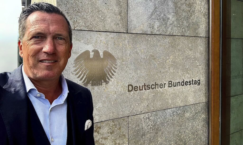 Politiker vor dem Deutschen Bundestag mit Bundesadler-Emblem.
