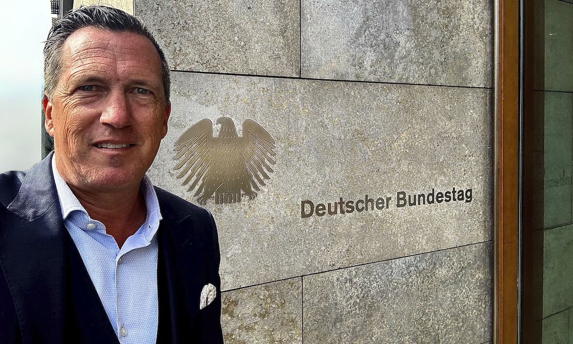 Politiker vor dem Deutschen Bundestag mit Bundesadler-Emblem.